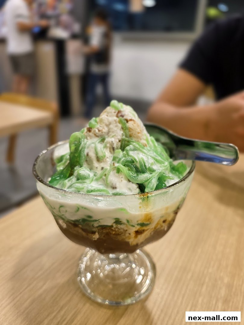A refreshing bowl of Cendol dessert with shaved ice and coconut milk.