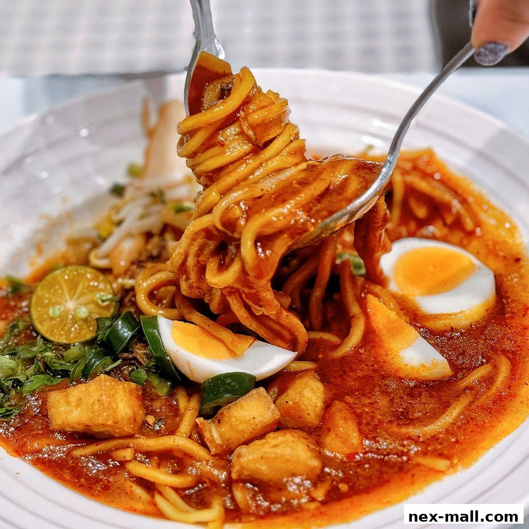 A close-up of a delicious bowl of noodles with egg, tofu, and chili.