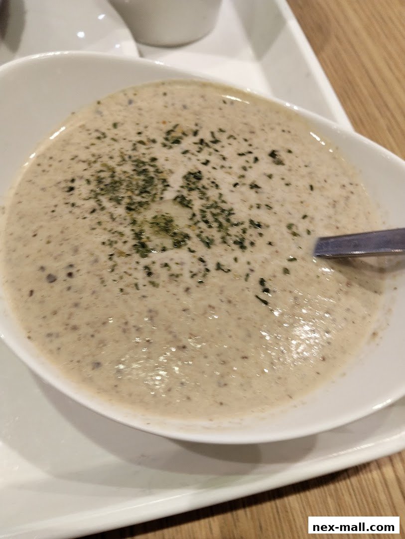A close-up shot of a creamy mushroom soup topped with herbs in a white bowl.