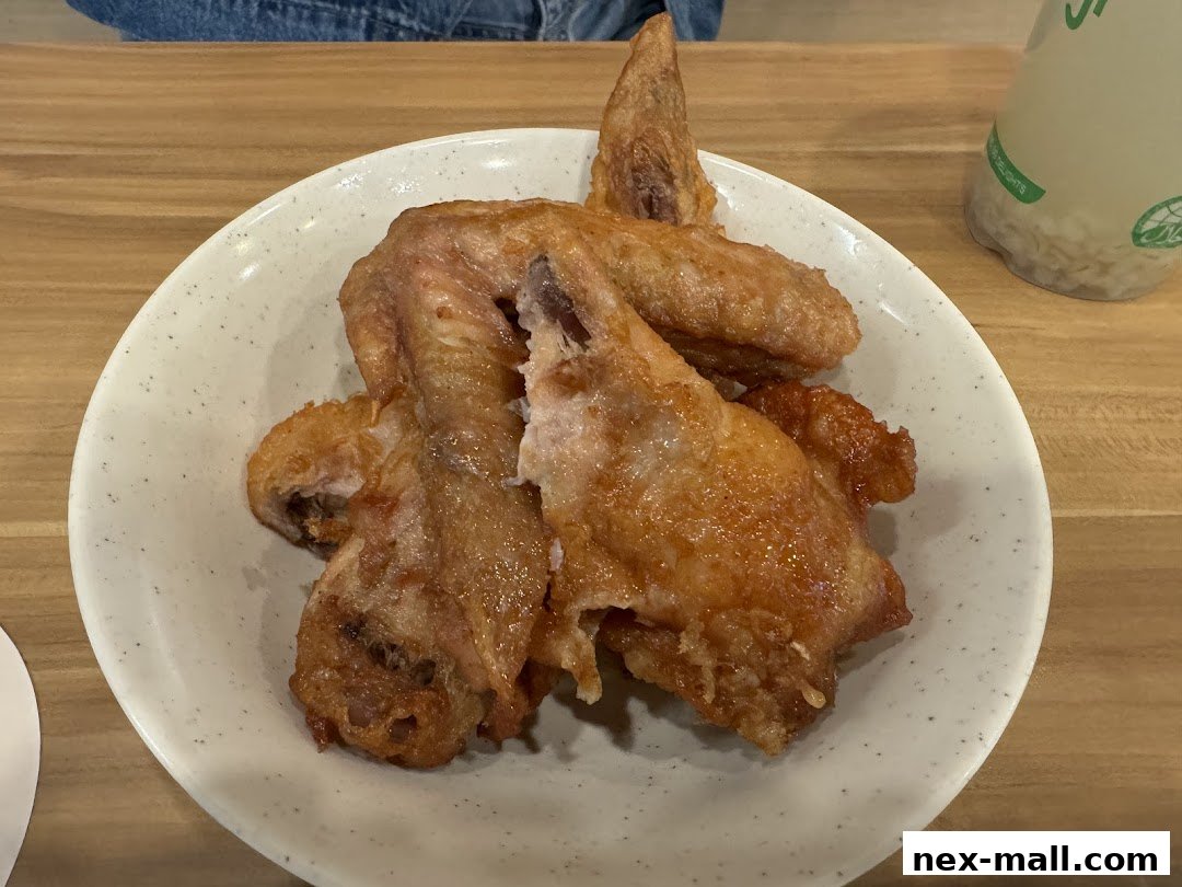 A close-up shot of crispy fried chicken wings served on a speckled white plate.