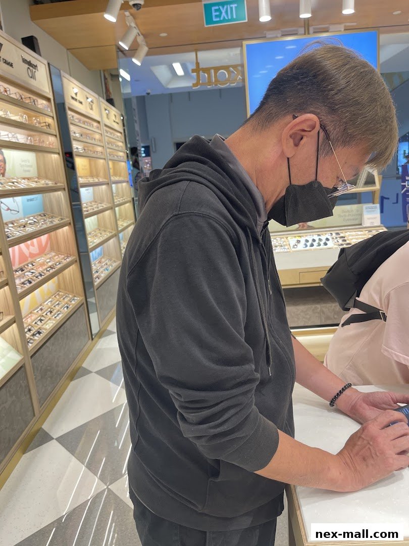 A man wearing a mask and glasses browses eyewear displays in a modern optical shop.
