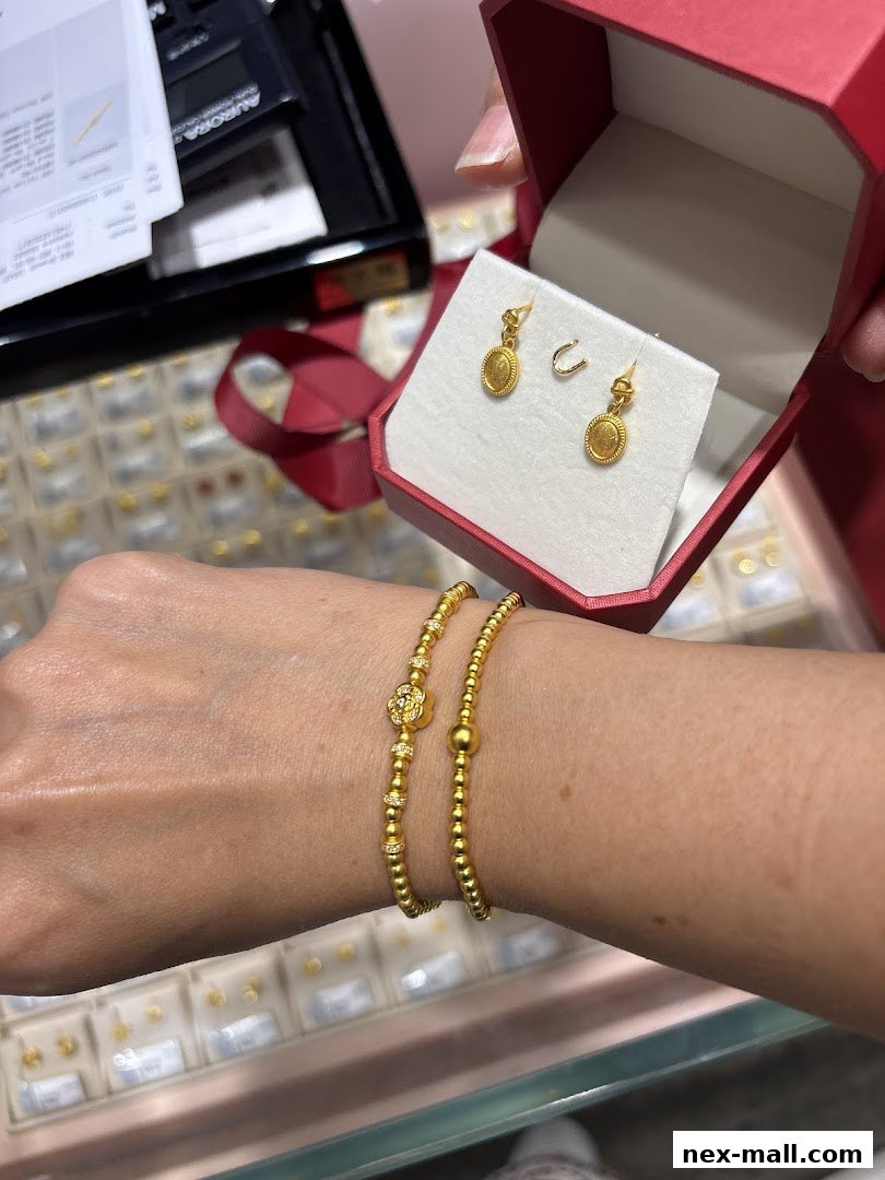 A hand wearing gold bracelets displays a red jewelry box with gold earrings.