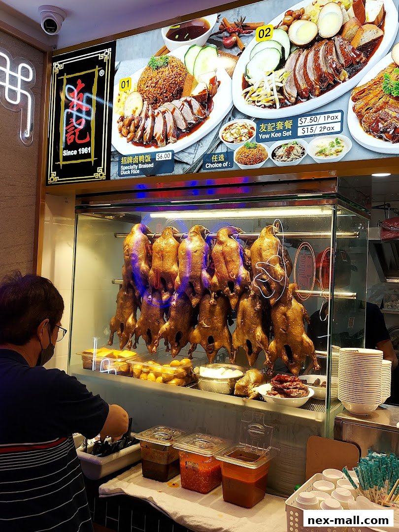 A shop counter displaying roasted ducks and a menu board with duck rice and set meals.