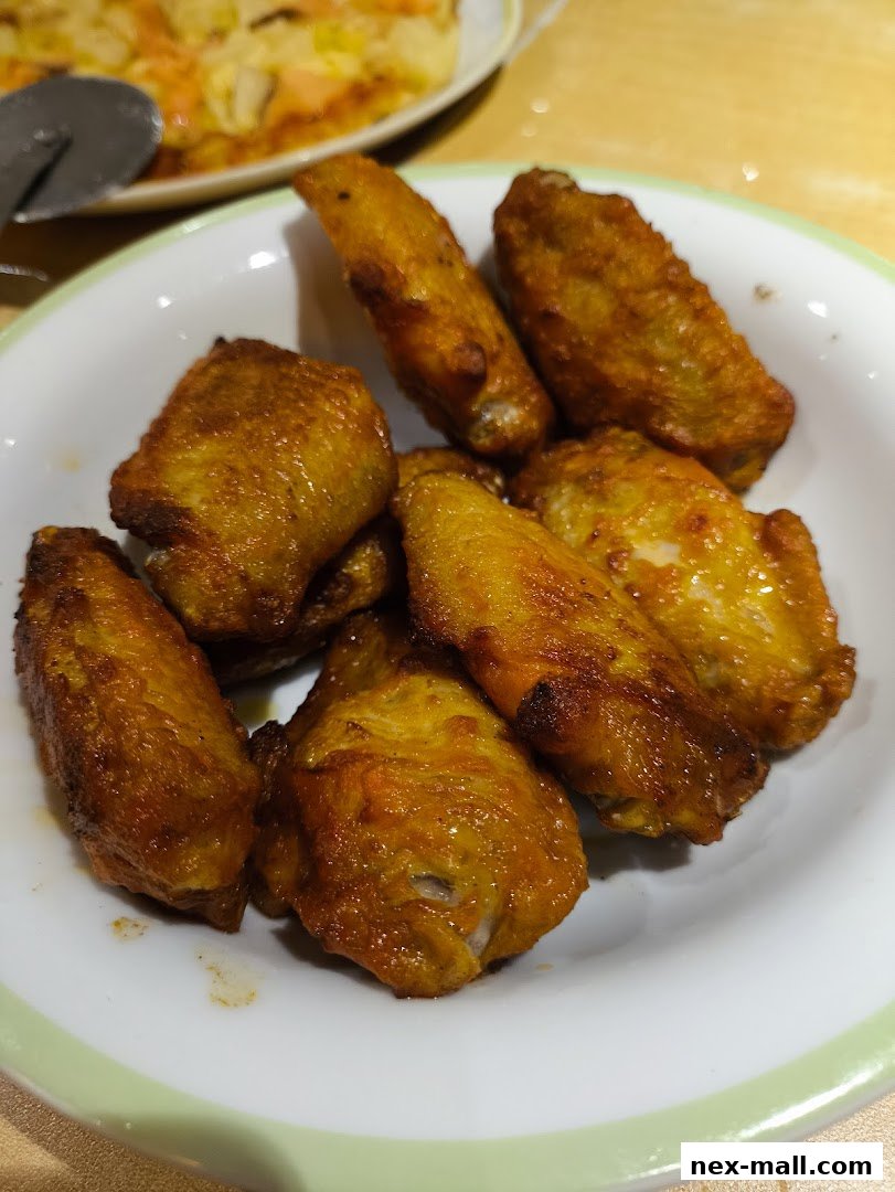 A close-up shot of a bowl filled with golden-brown, crispy chicken wings.