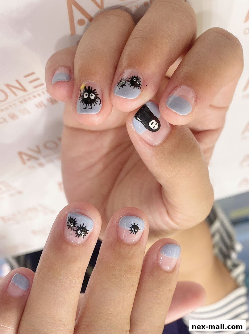 Close-up of hands with light blue and clear manicured nails featuring cute soot sprite nail art.