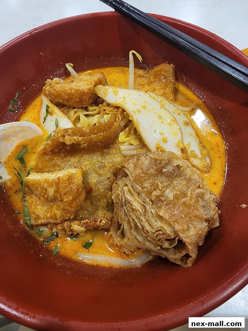 A close-up shot of a delicious bowl of curry noodles with various toppings and chopsticks.