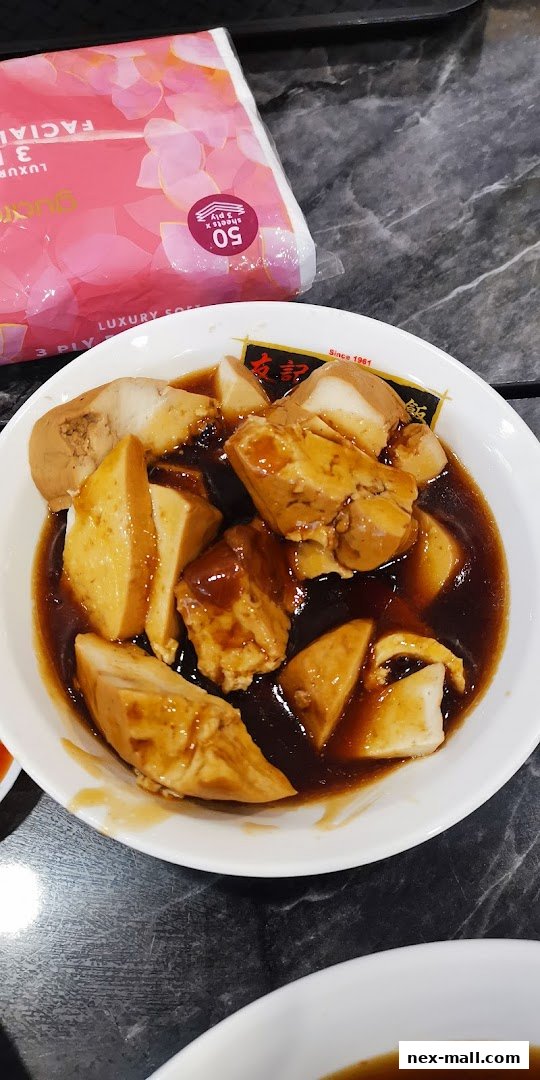 A close-up shot of braised tofu and eggs in a savory sauce, served in a white bowl.