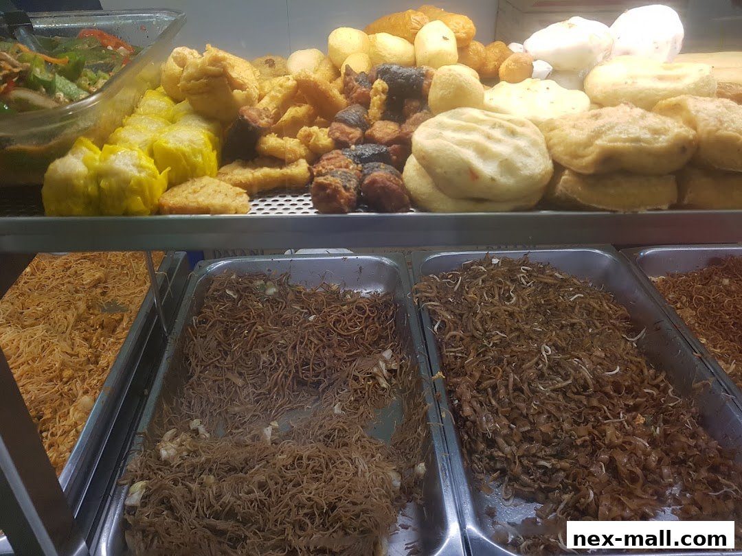A display of various prepared foods, including noodles, fried items, and dim sum.