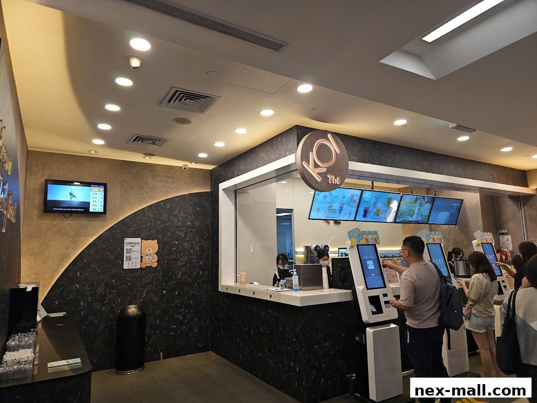 Customers ordering at self-service kiosks in a modern KOI Thé bubble tea shop.