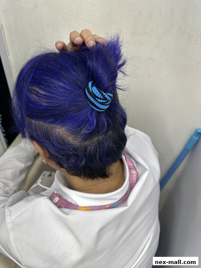 A person with vibrant blue hair tied up with a blue and black scrunchie.