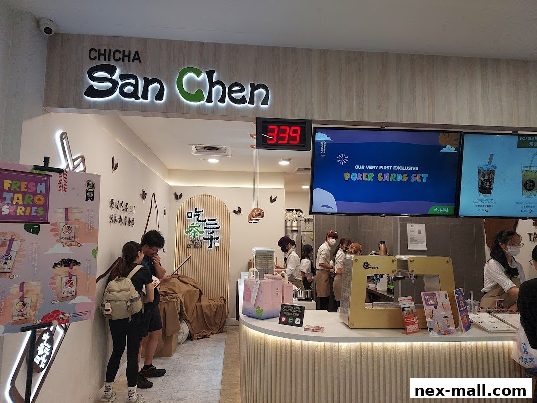 The entrance of CHICHA San Chen, a bubble tea shop, with staff and customers visible.