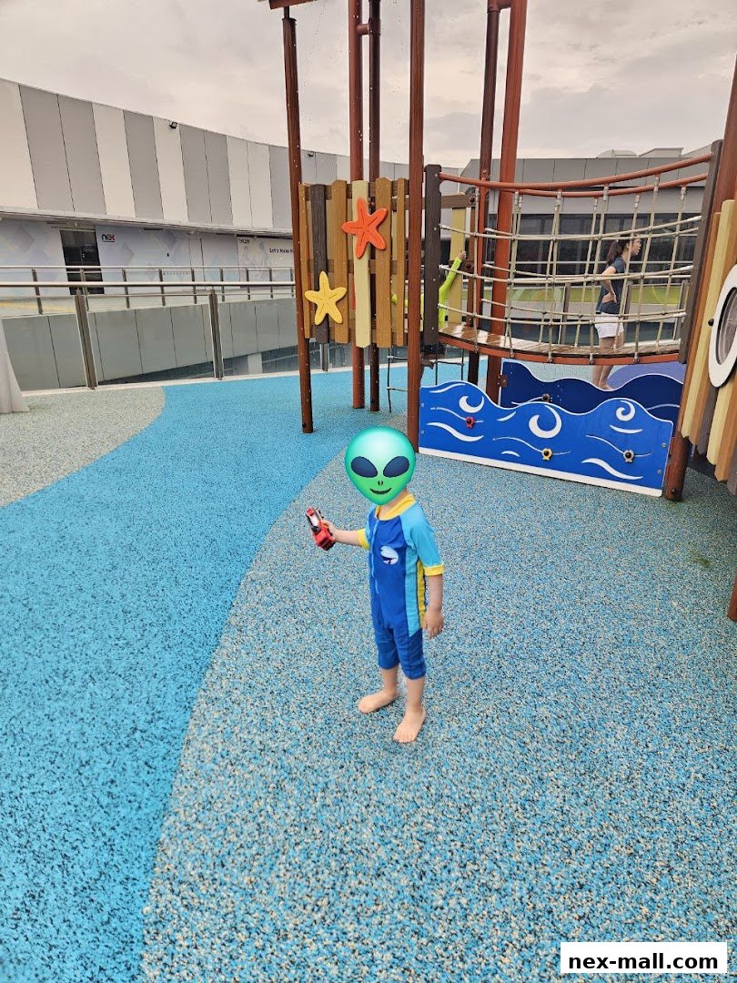 A child in a swimsuit stands on a blue playground with climbing structures.