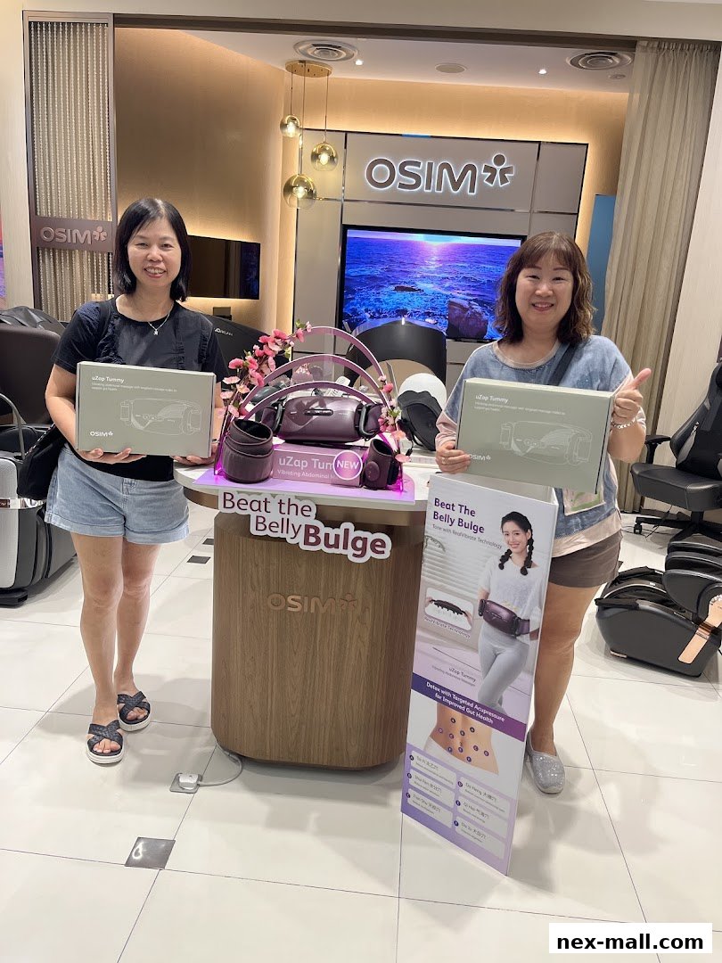 Two women holding OSIM uZap Tummy boxes in front of a display.
