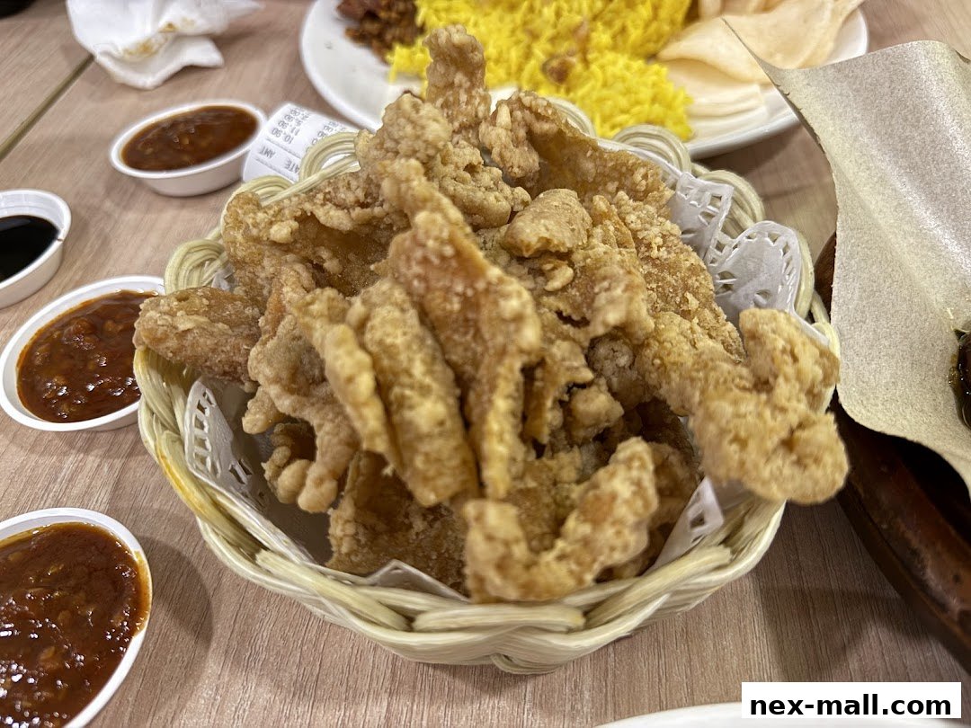A basket of crispy fried chicken pieces served with dipping sauces and a side of rice.