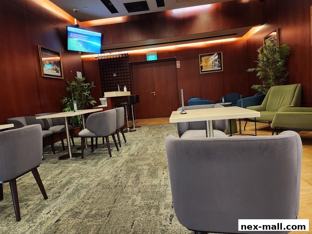 A comfortable waiting lounge with plush seating, tables, and a television screen.