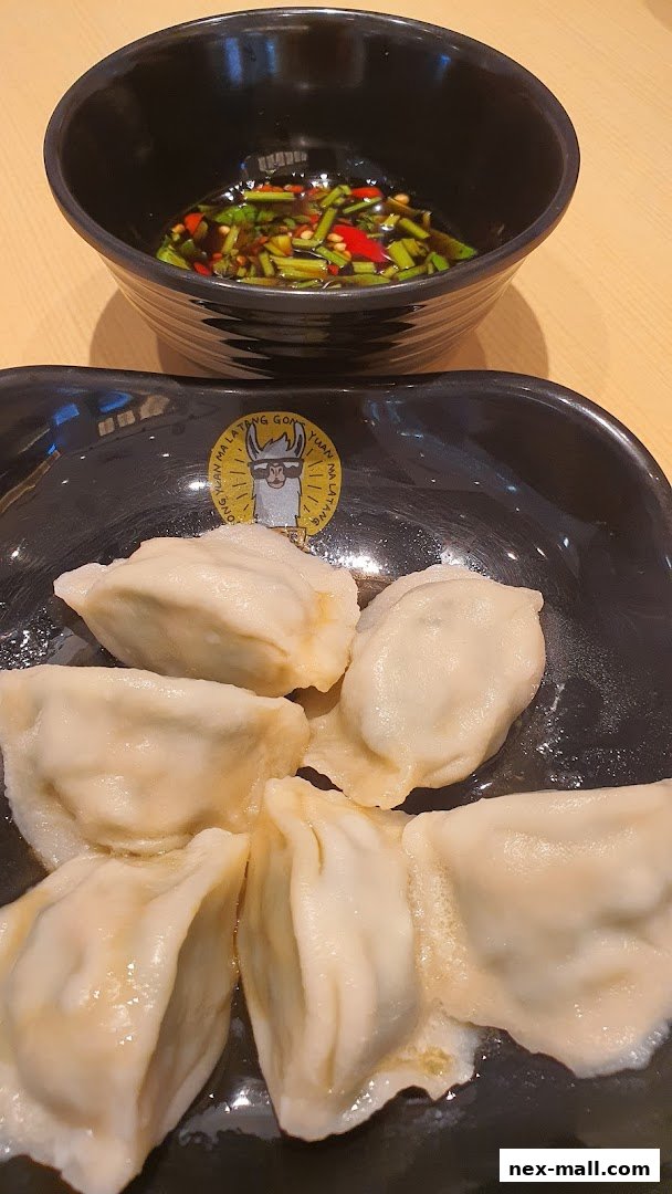 A plate of dumplings with a dipping sauce, featuring the restaurant's llama logo.