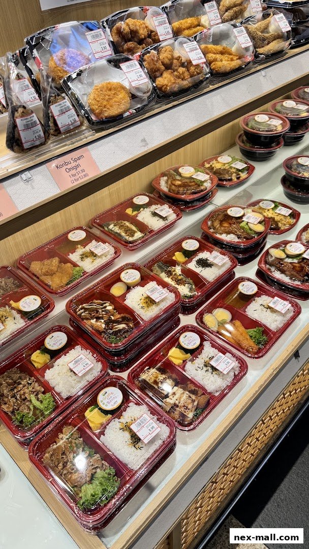A display of various pre-packaged Japanese bento boxes and onigiri with prices visible.