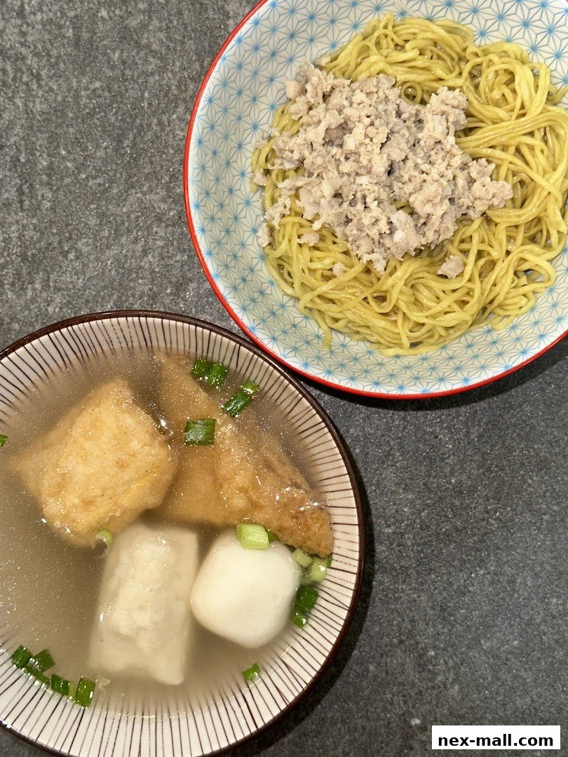 A bowl of noodles with minced meat and a side of soup with tofu and fish cakes.