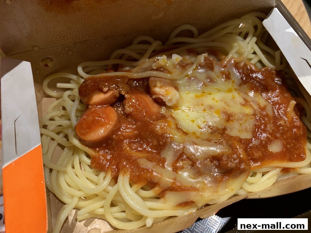 A close-up of Jollibee's spaghetti with hotdog slices and melted cheese.