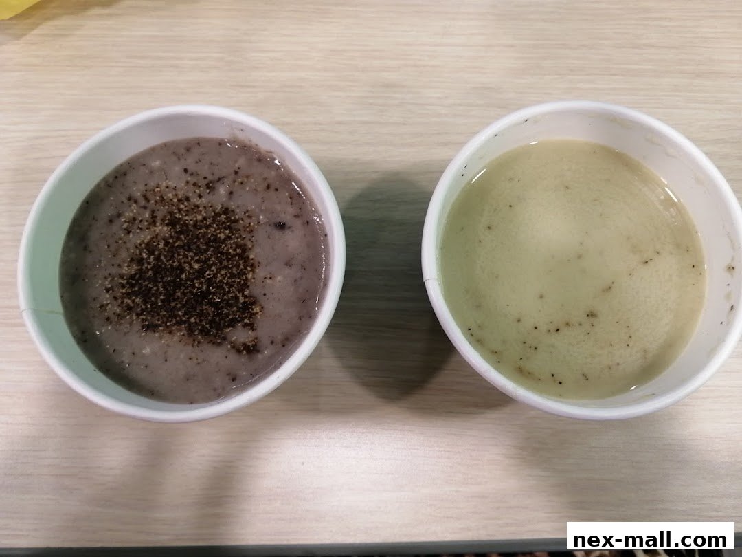 Two bowls of soup, one topped with pepper, sit on a wooden surface.