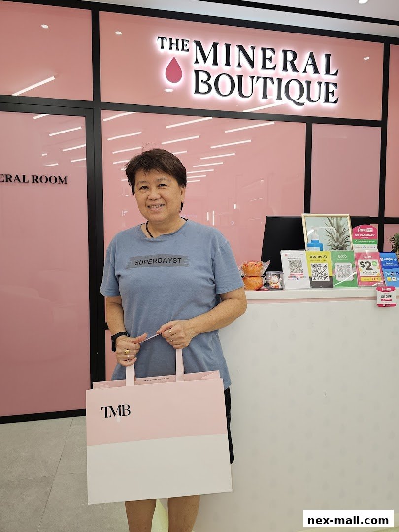 A woman stands in front of The Mineral Boutique, holding a branded shopping bag.