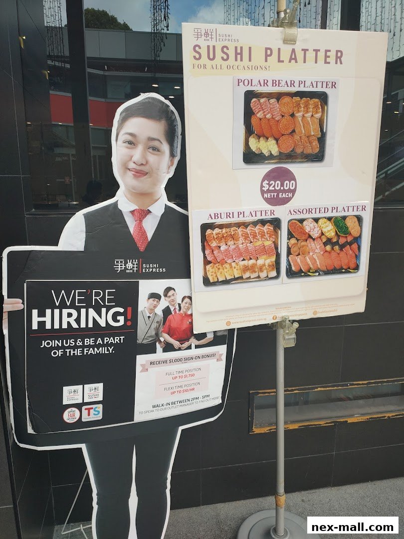 A cutout of a smiling staff member holding a hiring sign next to a sushi platter display.