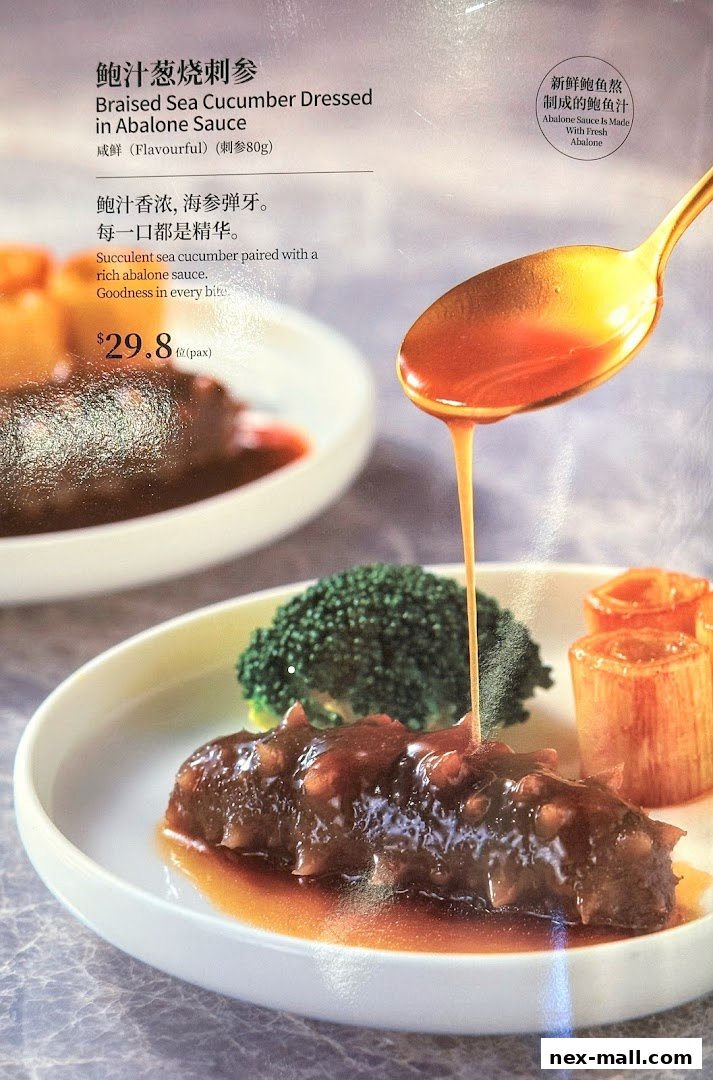 A close-up of a dish featuring braised sea cucumber in abalone sauce, served with broccoli and leeks.