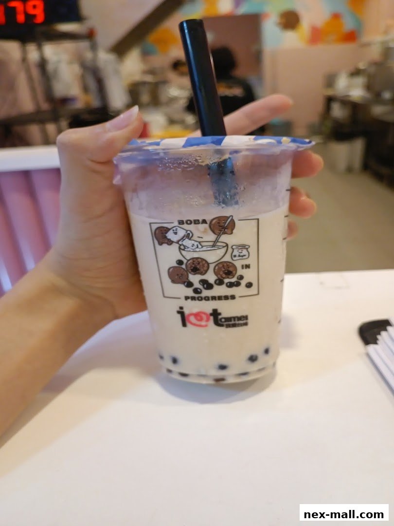 A hand holds a refreshing boba tea with the shop's logo visible.
