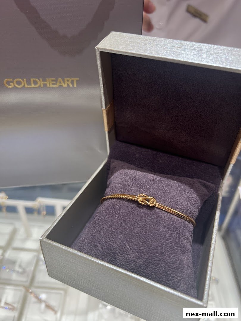 A gold bracelet with a knot design displayed in an open jewelry box.
