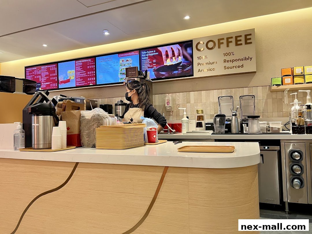 A Tim Hortons counter with a barista, digital menus, and coffee-making equipment.