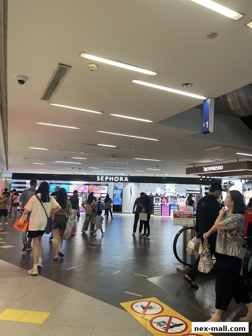 People walking past the Sephora store entrance in a brightly lit shopping mall.