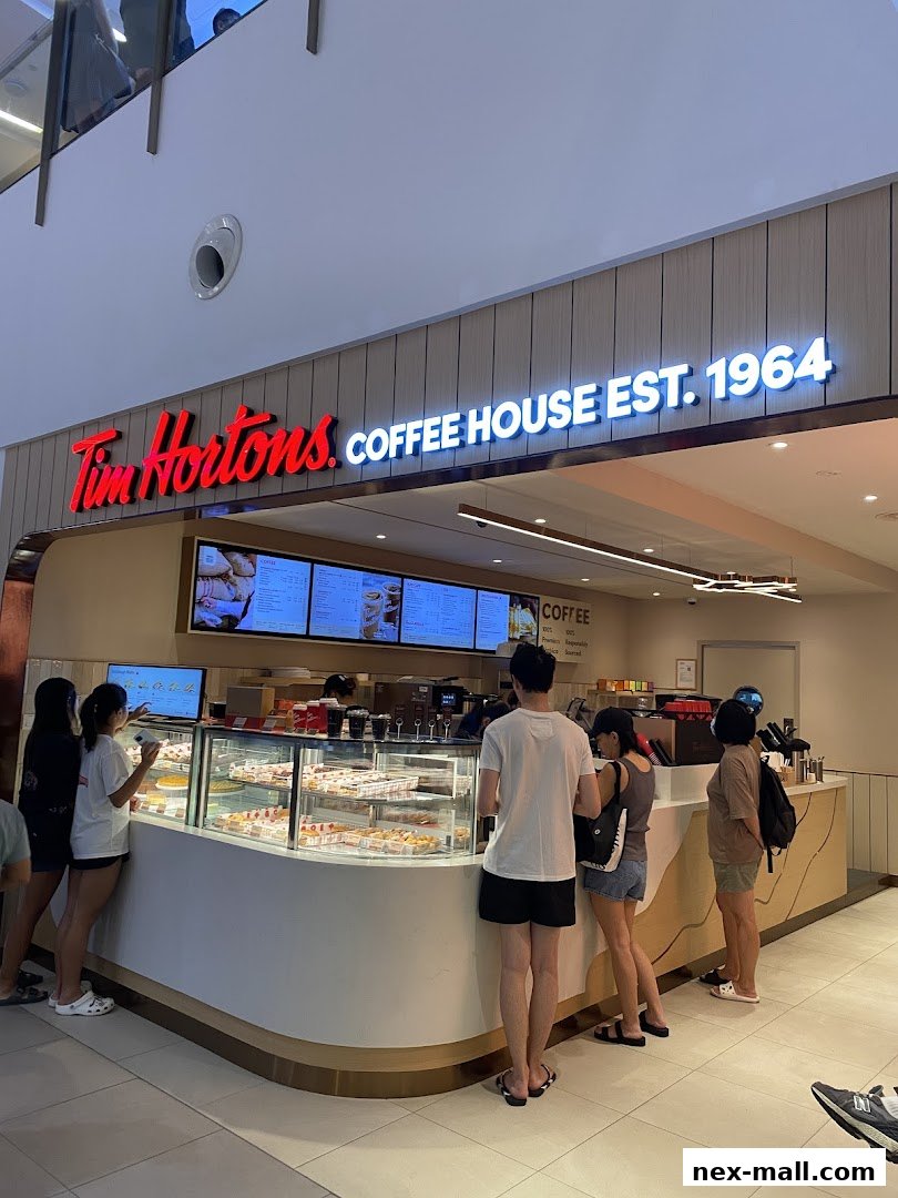 Customers queue at Tim Hortons coffee house, with a display of donuts and pastries.