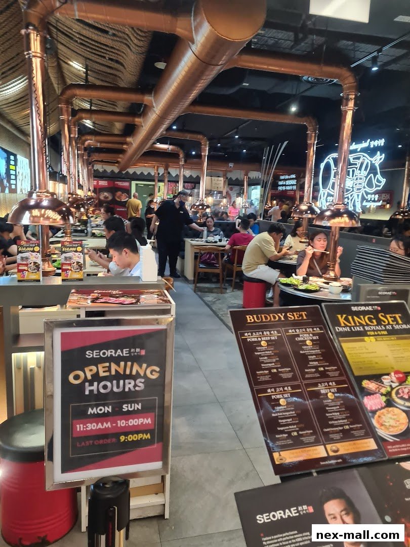 Interior of a busy Korean BBQ restaurant with diners and copper ventilation pipes.