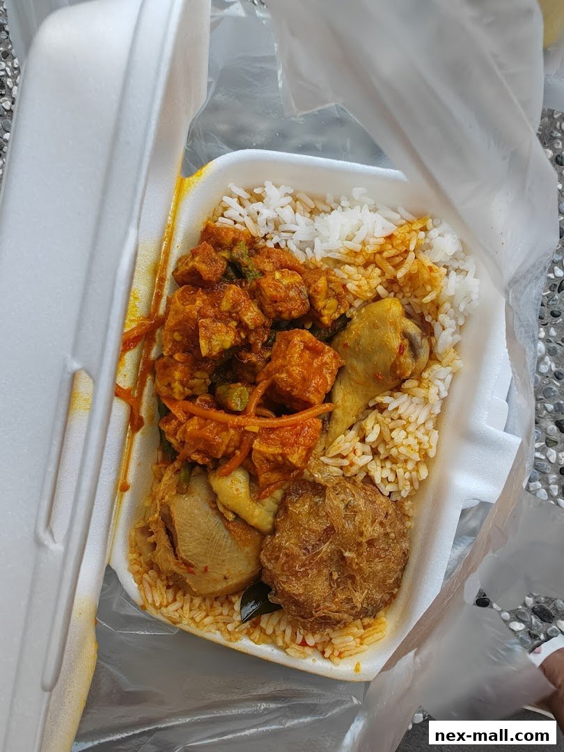 A takeaway container filled with rice, chicken, and various side dishes.