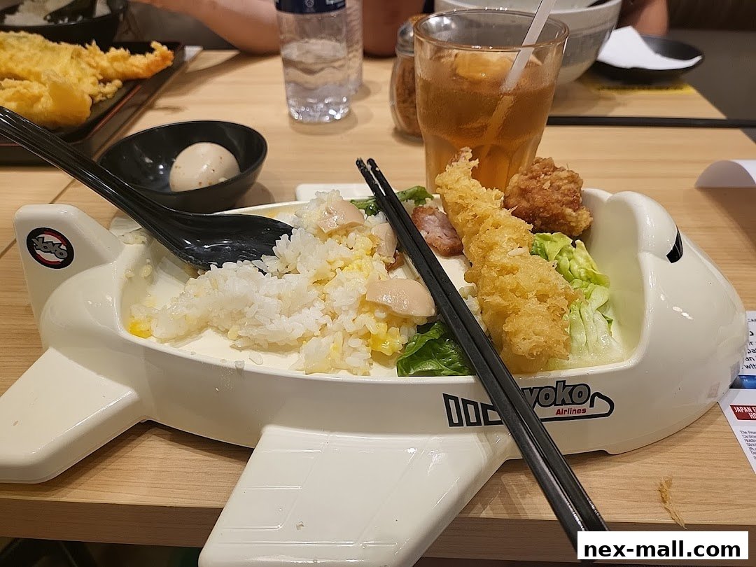A Japanese meal served in a unique airplane-shaped dish with rice, tempura, and chicken.