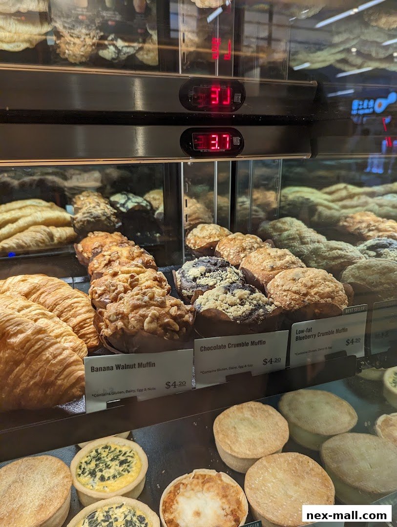 A display case filled with various pastries, including muffins, croissants, and small pies.