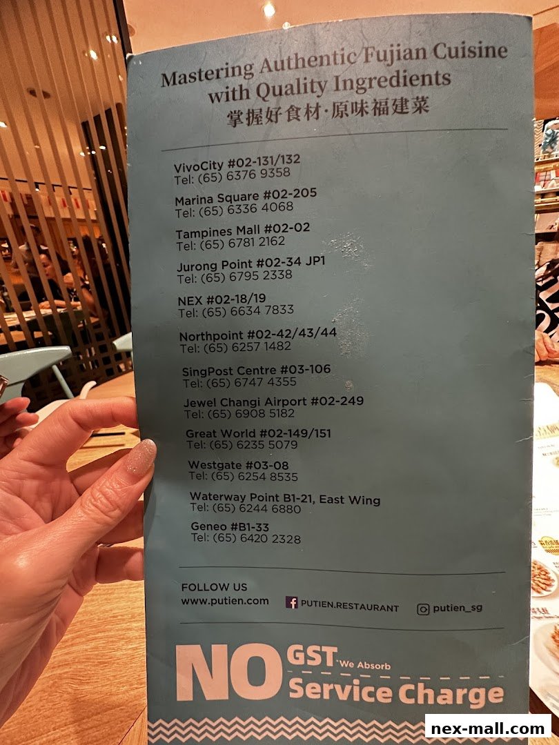 A person holds a menu listing PUTIEN restaurant locations and contact information.
