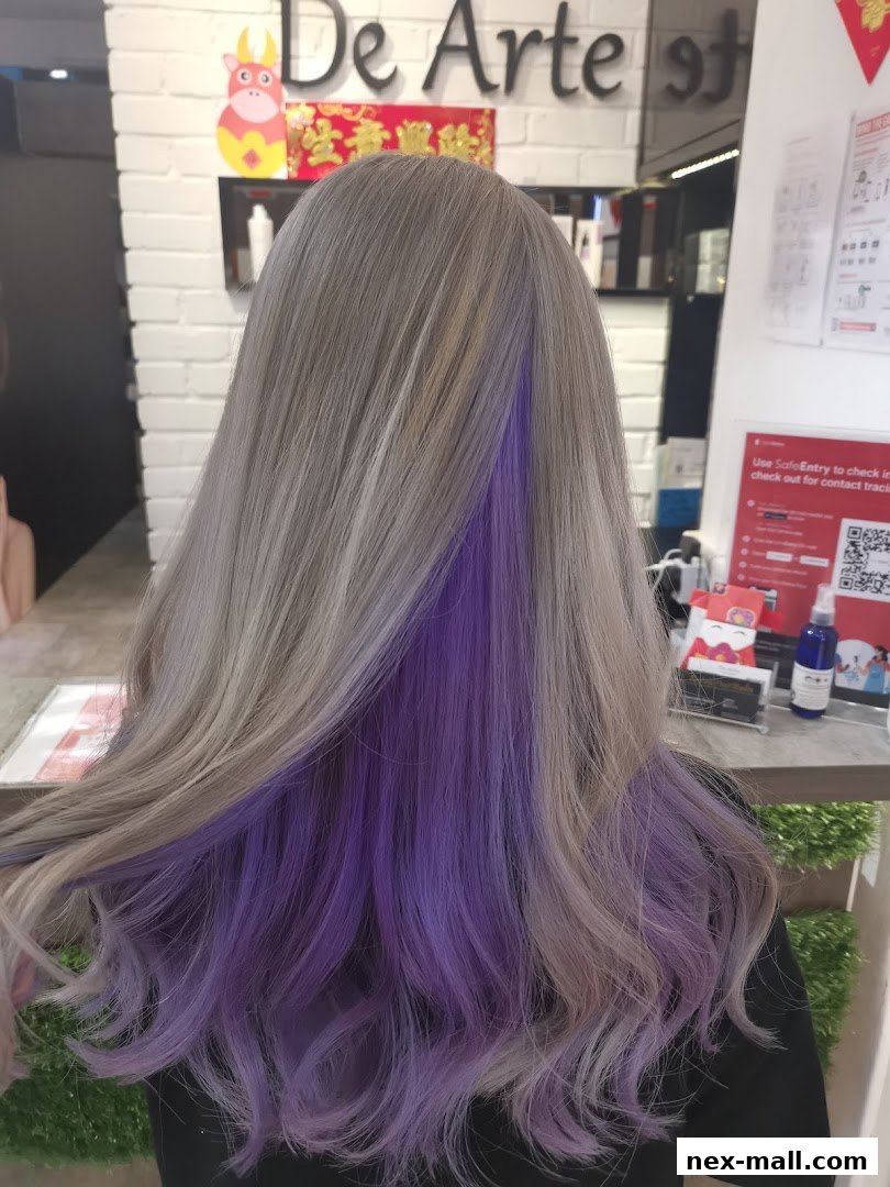 A person with stylish ash blonde hair featuring vibrant purple highlights underneath.