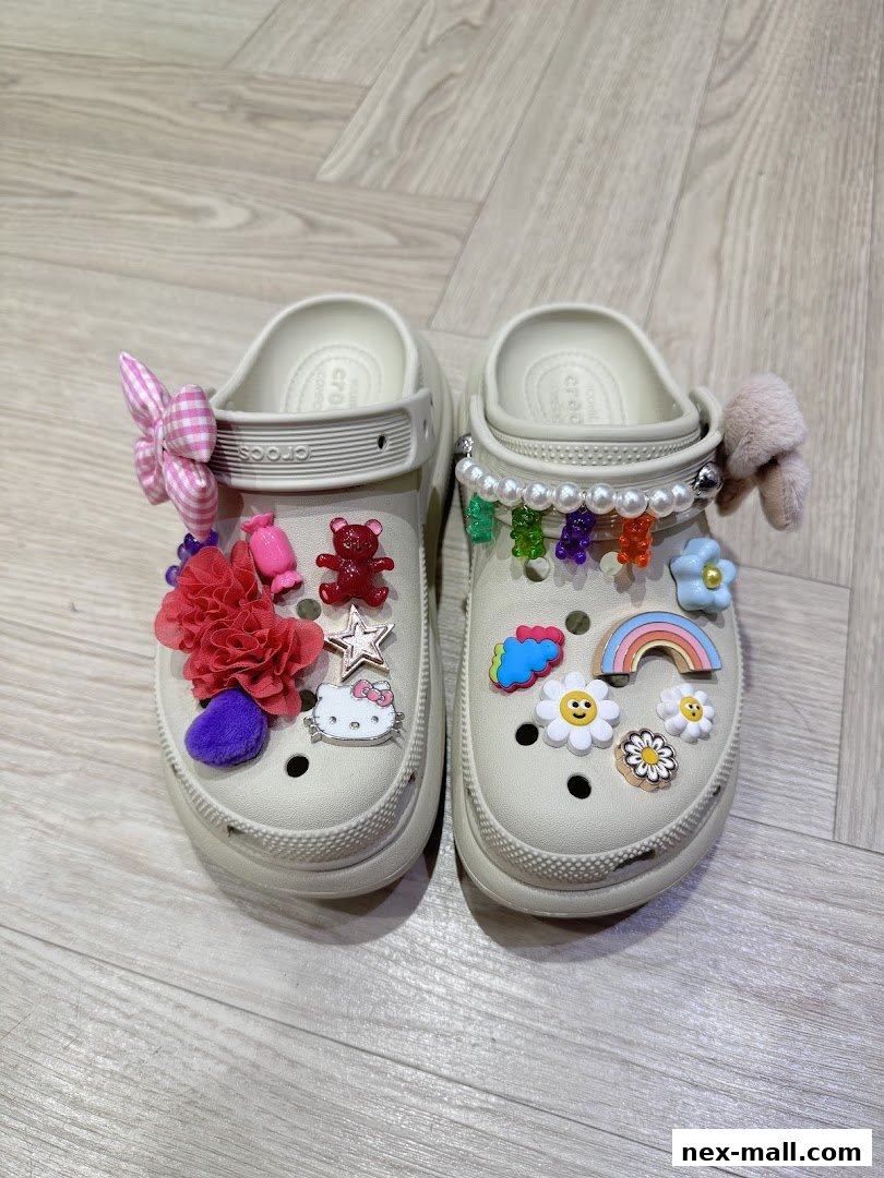 A pair of beige Crocs adorned with colorful Jibbitz charms and accessories.