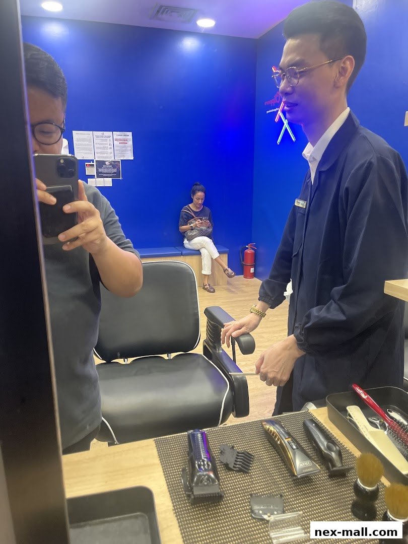 Barber shop interior with a barber, client, and waiting customer.