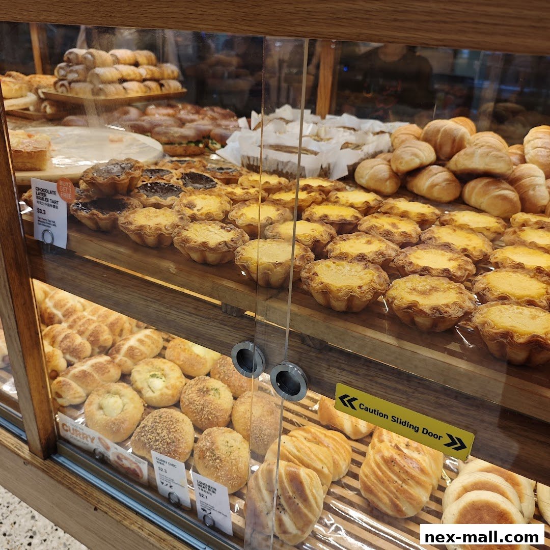 A display case filled with a variety of freshly baked pastries and bread, including tarts and buns.