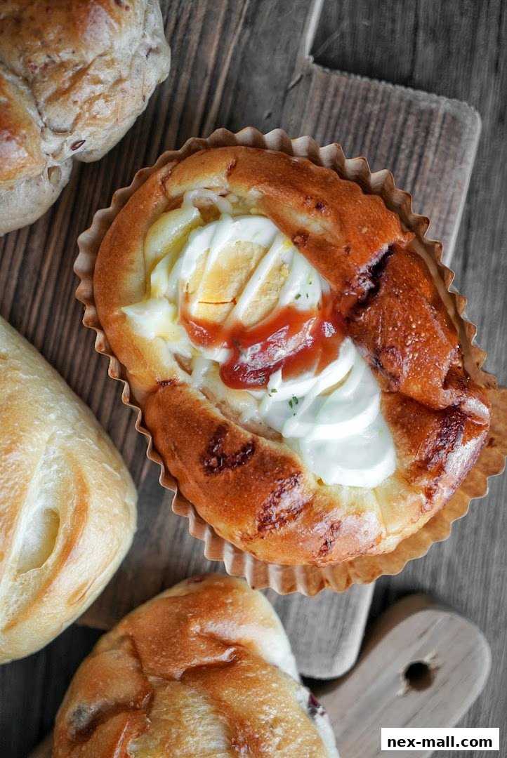 A close-up overhead view of a savory Japanese bakery bun with egg and sauce.