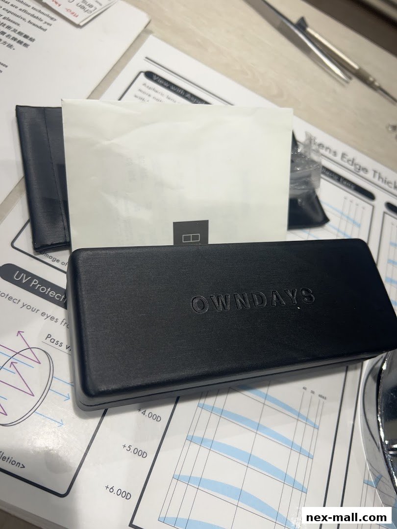 A black OWNDAYS glasses case rests on informational charts about lenses.