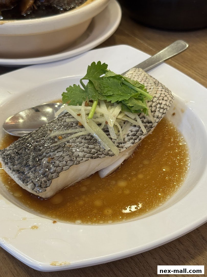 A close-up of a steamed fish dish with ginger, scallions, and cilantro.