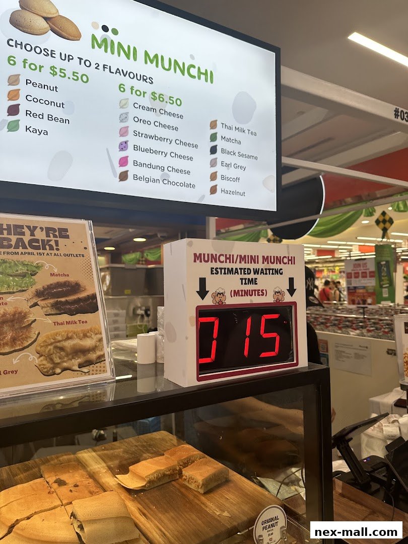 A menu board displays various flavors of Mini Munchi pancakes with pricing and a waiting time display.