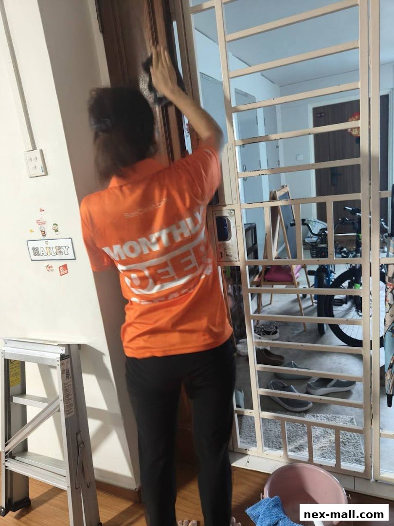 A person in an orange shirt cleans a door frame with a cloth.
