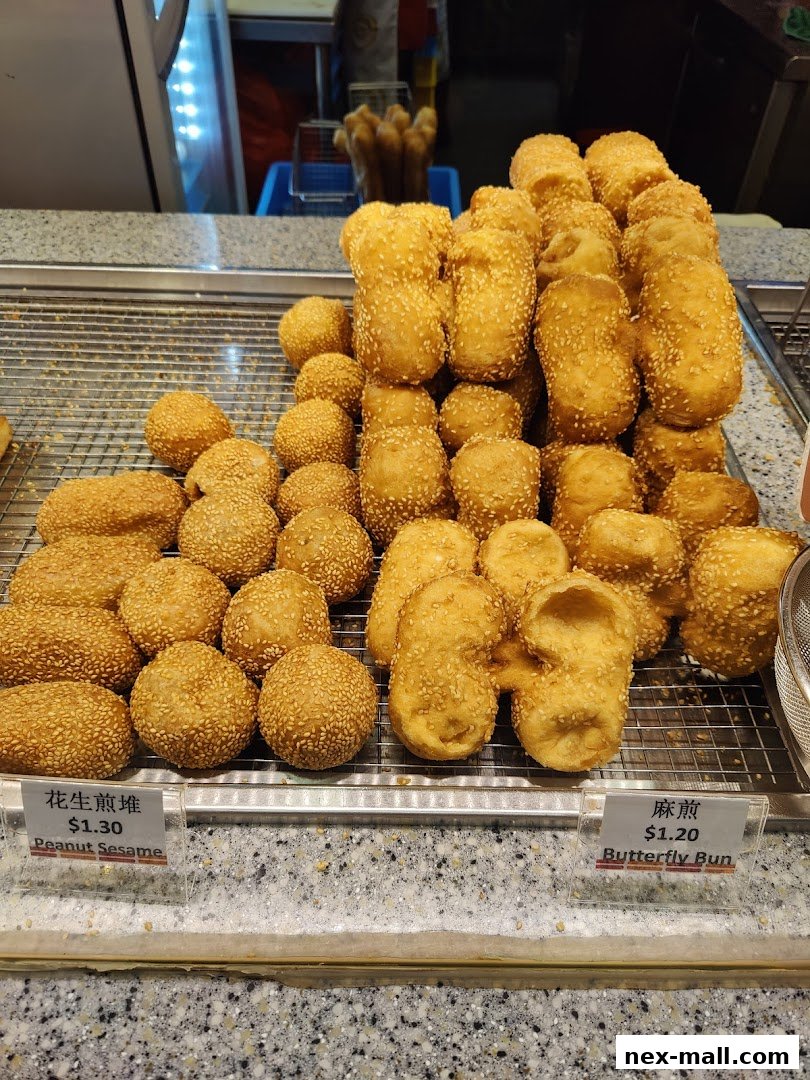 A display of freshly fried sesame-coated pastries, including round peanut sesame balls and butterfly buns.