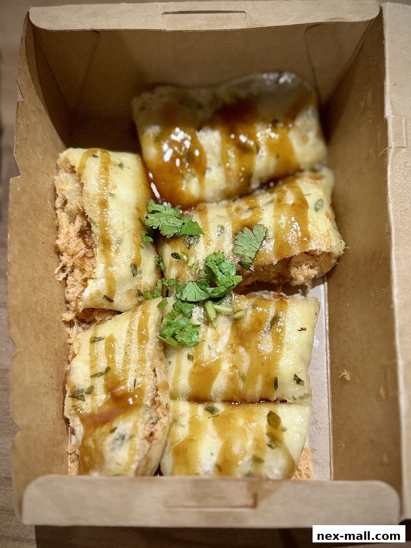 A close-up shot of Taiwanese street snacks, likely crispy rolls with sauce and herbs.
