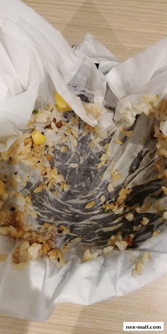 A close-up of a paper-lined bowl with leftover rice and corn.