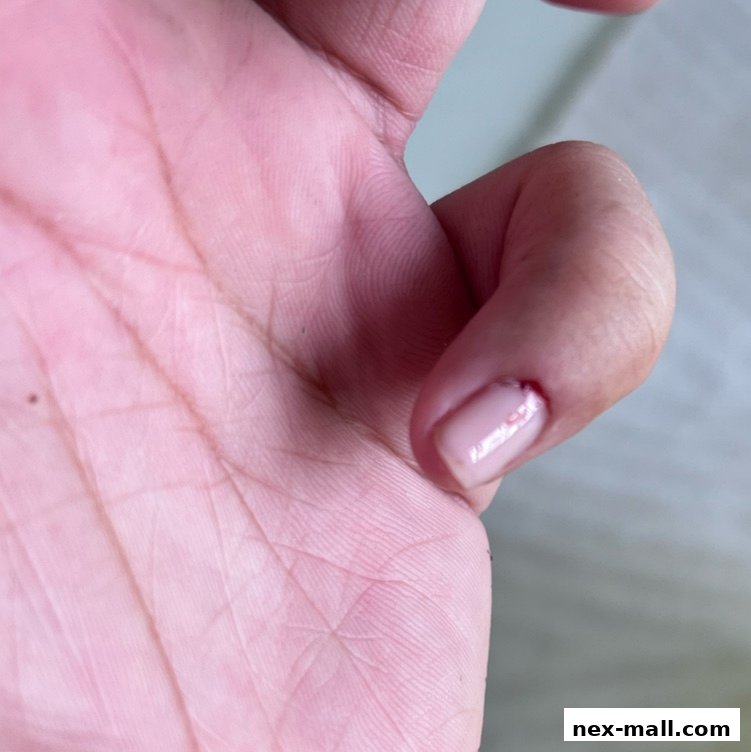A close-up shot of a person's hand with a freshly painted, light pink nail.